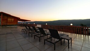 Terraza con sillones de descanso y barandilla de madera con vistas a un paisaje montañoso.