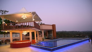 Un hotel moderno con piscina, mobiliario exterior y terraza cubierta.
