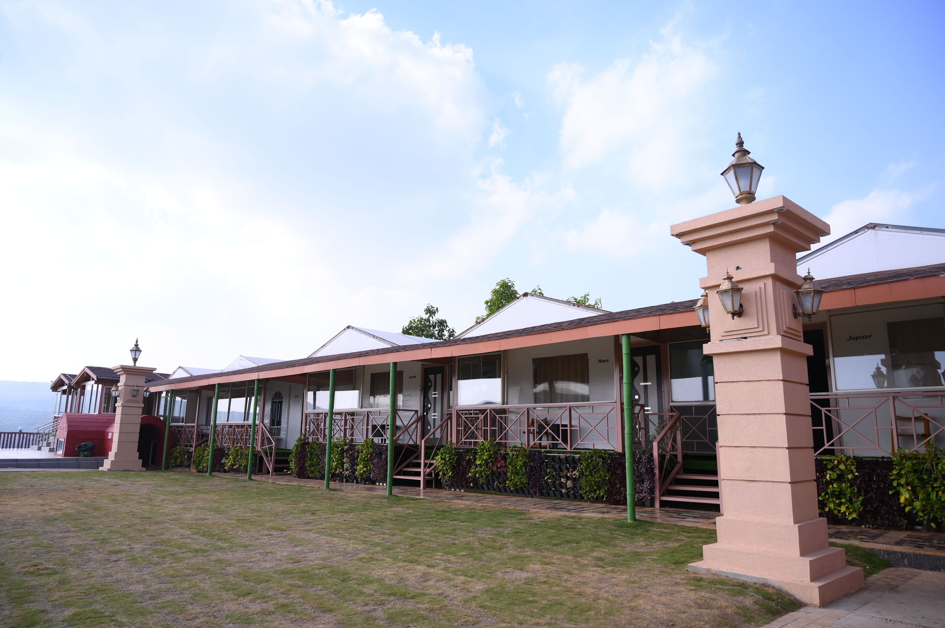 A coastal hotel with a covered outdoor area, a staircase leading to the entrance, and a view of the sea.