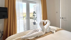 A hotel room with a bed, a television, and a view of the outdoors through a glass door. - The View (Bodmin)
