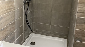 A shower with a white basin and a black hose. - LES IRIS ANNEMASSE (Annemasse)