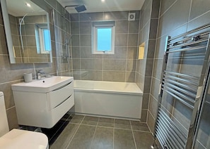 Uma casa de banho moderna com uma toucador branca, uma banheira e um chuveiro com parede de vidro.