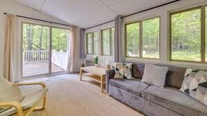 A spacious living room with a grey sofa, a wooden coffee table, and a view of a balcony with a white fence.