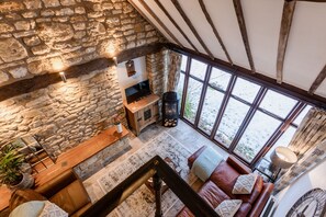 Une pièce chaleureuse avec des murs en pierre, un plafond en bois et de grandes fenêtres.