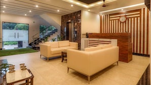 A modern living room with a sofa, a coffee table, and a reception desk. - KDS Residency (Greater Noida)