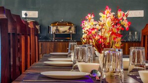 A dining table set with plates, glasses, and a vase of flowers. - KDS Residency (Greater Noida)