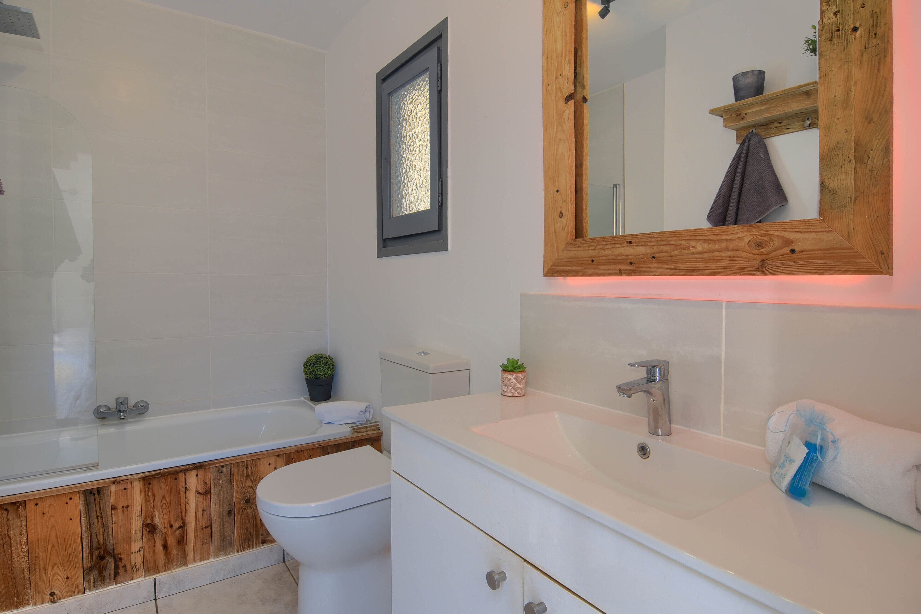 A bathroom with a wooden vanity, a white sink, and a bathtub.
