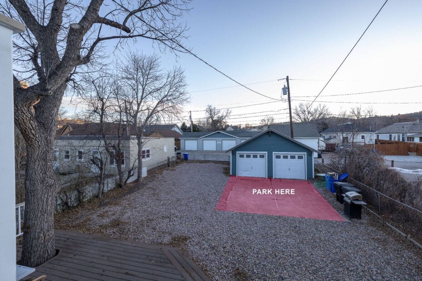 A residential area with a gravel driveway, a red parking area, and a small garage.