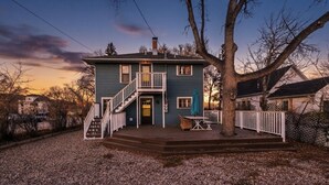 Ein zweigeschossiges Haus mit Veranda, Treppe und Baum davor.