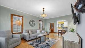 A living room with a sofa, armchair, and a dining area with a table and chairs.