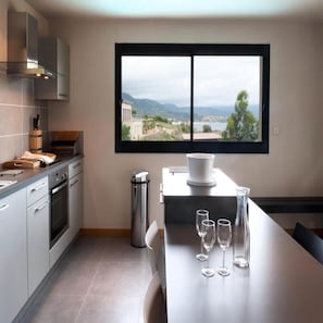 Una cocina moderna con un ventanal grande, una mesa de comedor con copas de vino y vistas al paisaje.