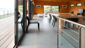 Une pièce spacieuse avec un grand plafond en bois, un coin repas comprenant une longue table et des chaises, un canapé et un téléviseur.