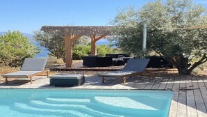 Un espace piscine avec des chaises longues et une pergola.