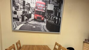 Een eethoek met een houten tafel en stoelen, een zwarte prullenbak en een grote zwart-wit foto aan de muur.