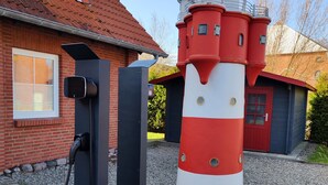 Ein Leuchtturm mit rot-weiß gestreifter Außenwand, verbunden mit einer schwarzen Schaltbox und einem Kabel.