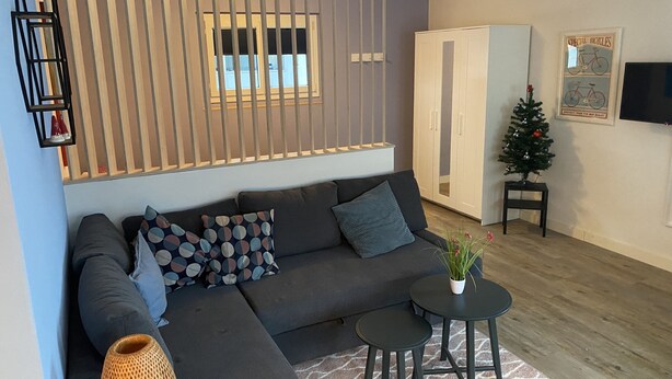 A modern living room with a sectional sofa, a small round table, and a decorative plant. - Modern studio in 1970s house in Haslital (Schattenhalb)