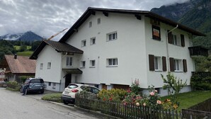 A two-story building with a white facade, multiple windows, and a sign indicating it is a hotel. - Modern studio in 1970s house in Haslital (Schattenhalb)