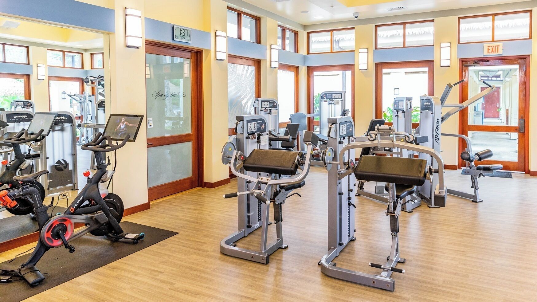 Une salle de sport équipée de machines de cardio, de postes d’entraînement avec poids et de miroirs.