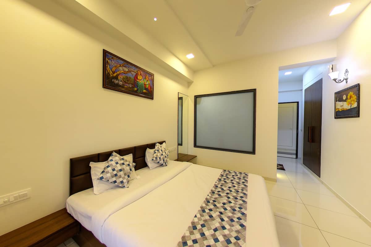 A hotel room with a large bed, a wall-mounted TV, a painting, and a mirror.