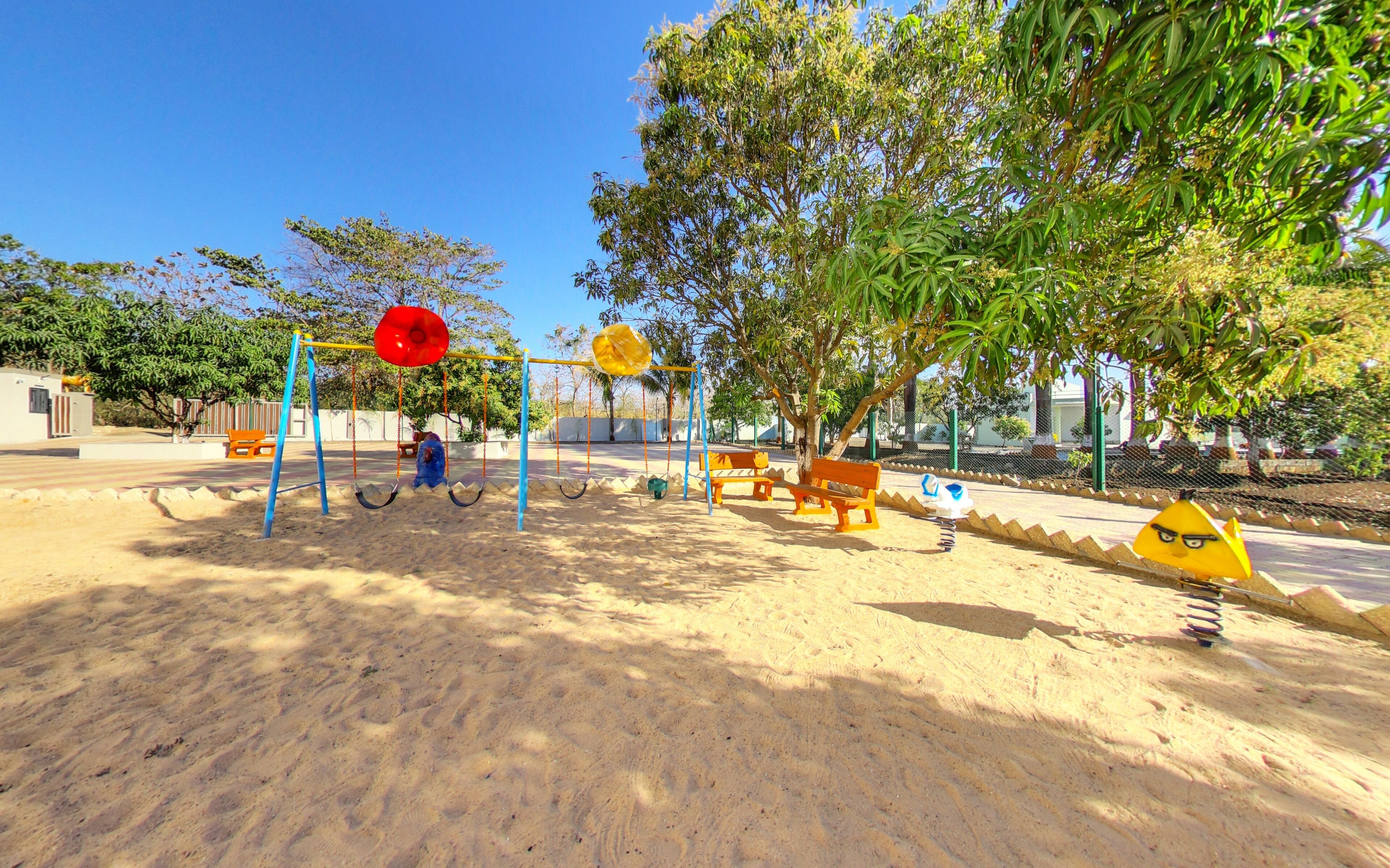 A playground with swings, a slide, and sand.