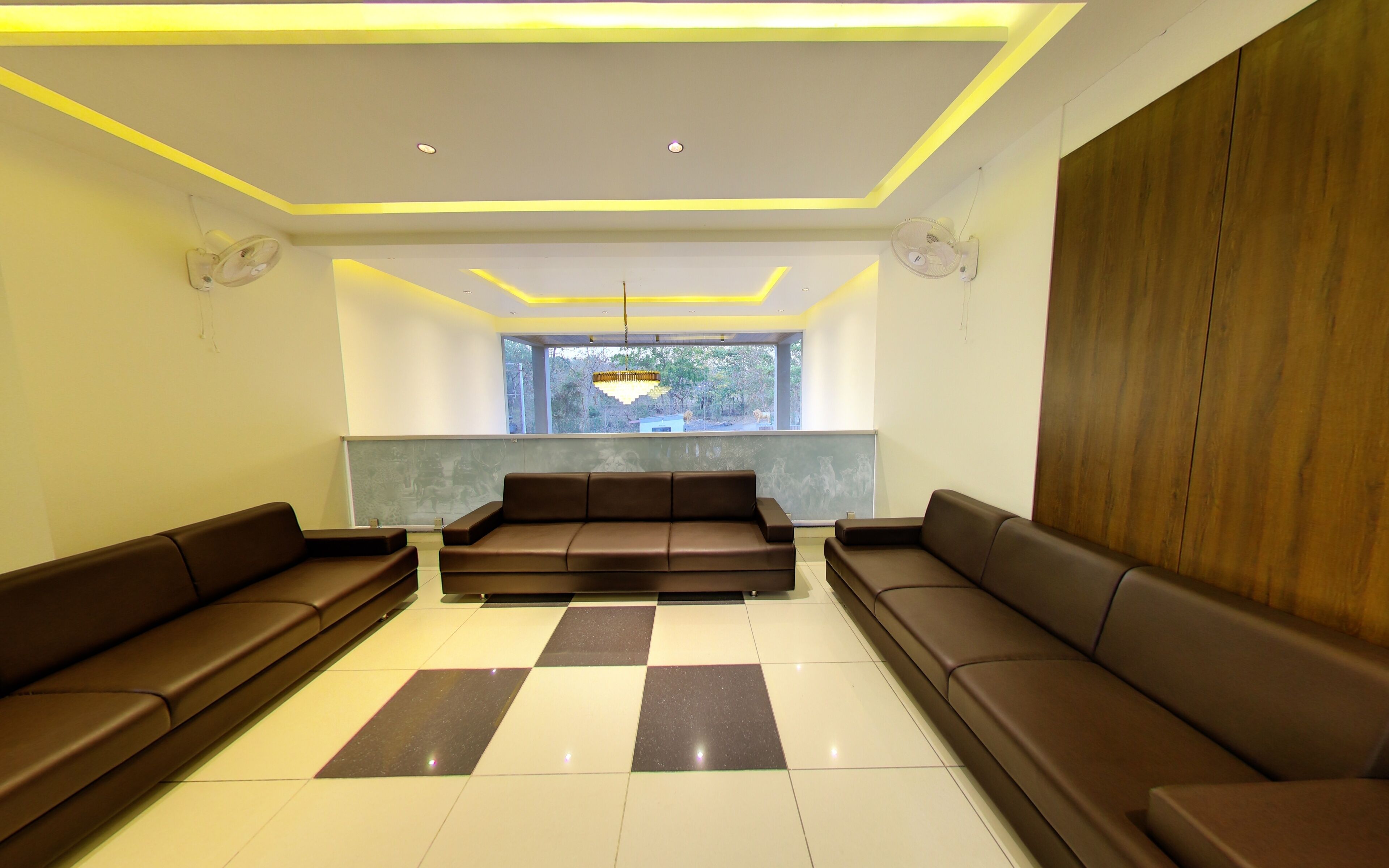 A modern waiting area with a checkered floor, a central sofa, and two wall-mounted fans.