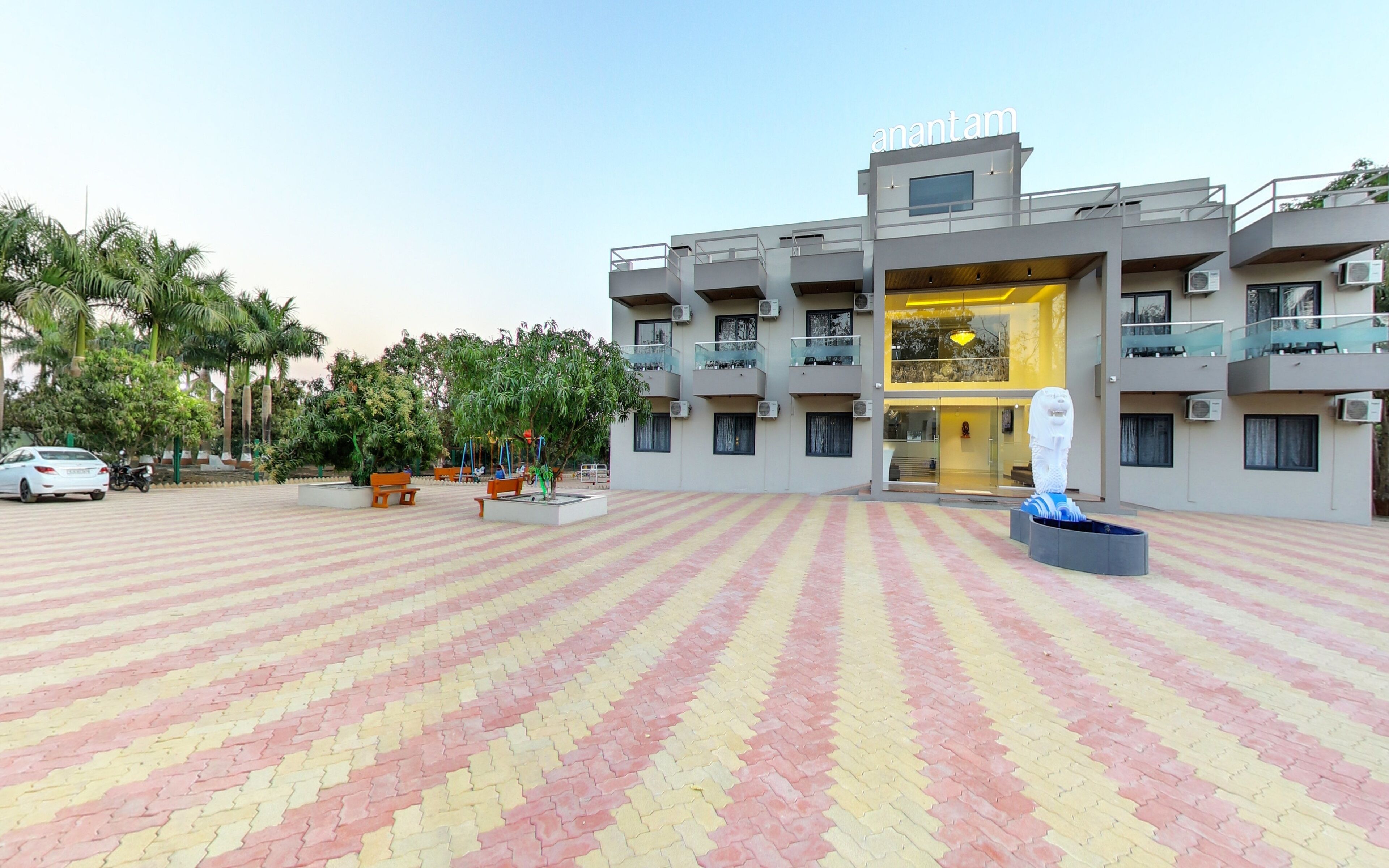 A modern building with a large open plaza, benches, and a statue.