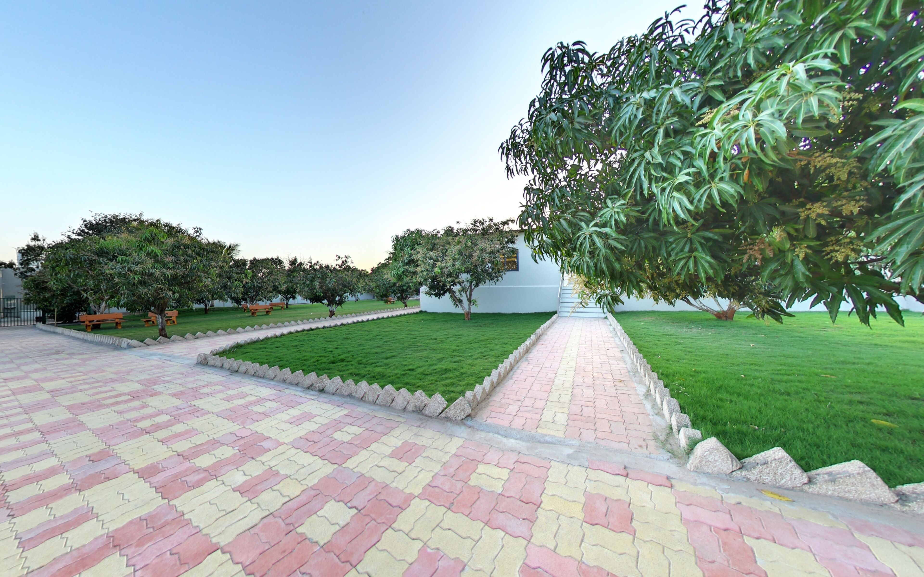 A paved courtyard with a central pathway, surrounded by green lawns and trees.