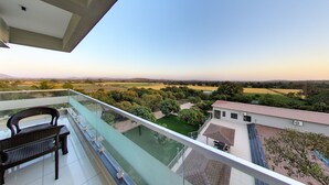 Un balcón con vistas a un paisaje verde y campos lejanos.