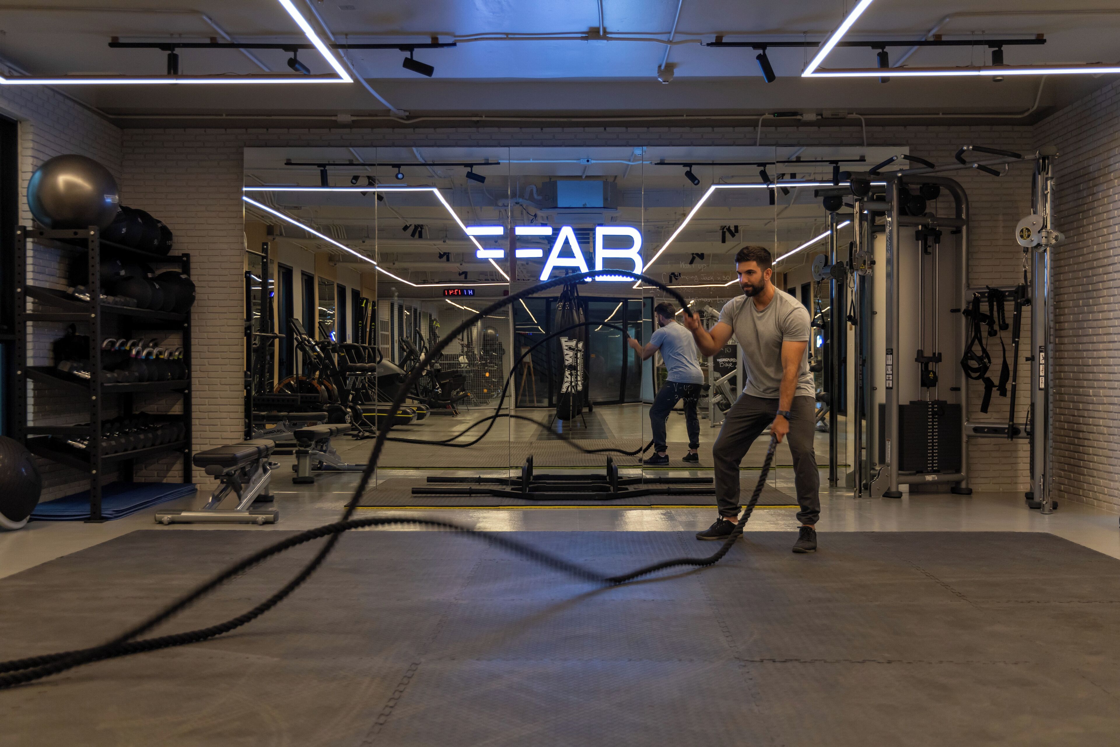 A gym with exercise equipment, a mirror, and a sign that reads "FEAR".