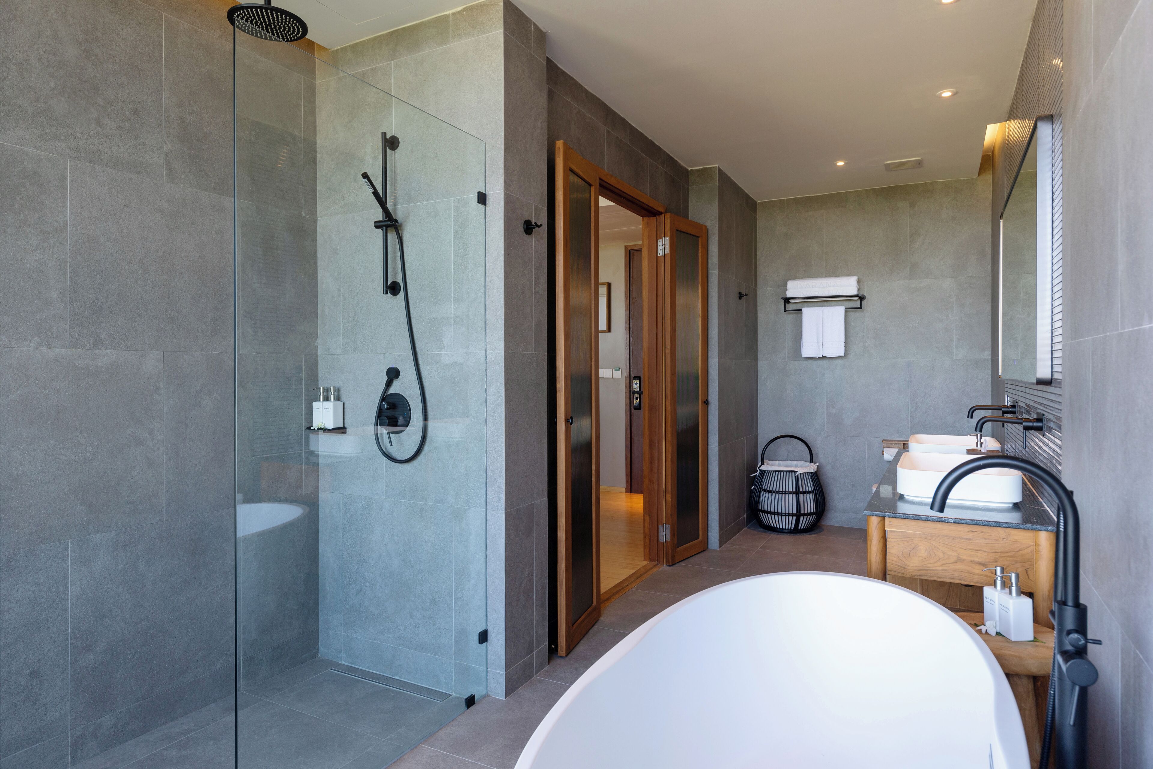A modern bathroom with a glass-enclosed shower, a freestanding bathtub, and a vanity with a mirror.