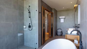 A modern bathroom with a glass-enclosed shower, a freestanding bathtub, and a vanity with a mirror.