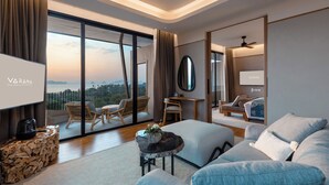 A modern hotel room with a large balcony, a flat-screen TV, a sofa, a coffee table, and a wooden side table. - Varana Hotel Krabi (Krabi)