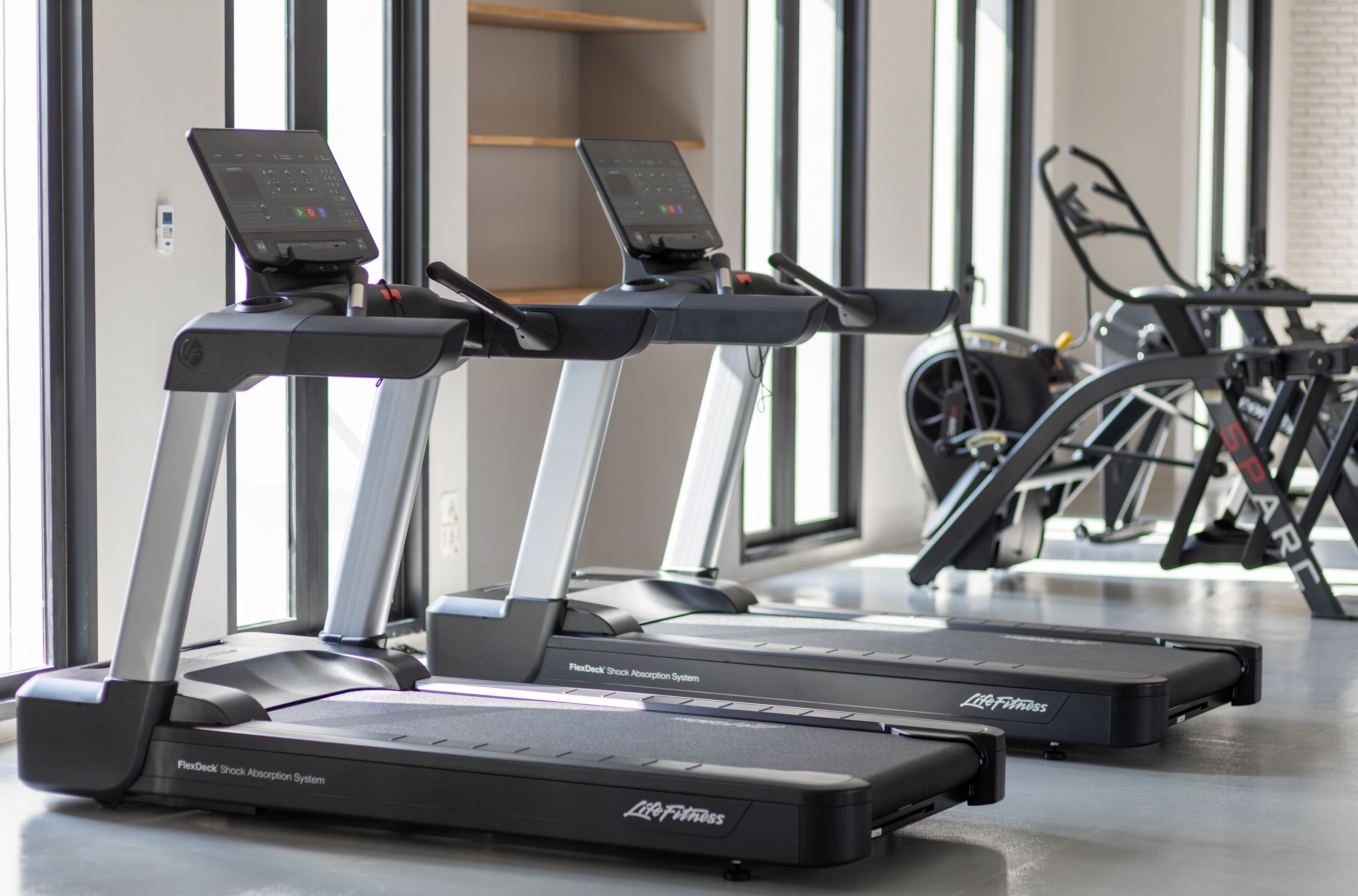 Tres cintas de correr Life Fitness con sistema de absorción de impactos FlexDeck en un gimnasio.