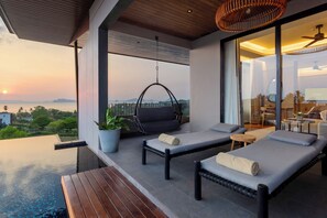 A modern balcony with two lounge chairs, a hanging chair, and a wooden table. - Varana Hotel Krabi (Krabi)