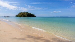 A beach with clear turquoise water, a sandy shore, and a small island with dense vegetation in the background. - Varana Hotel Krabi (Krabi)