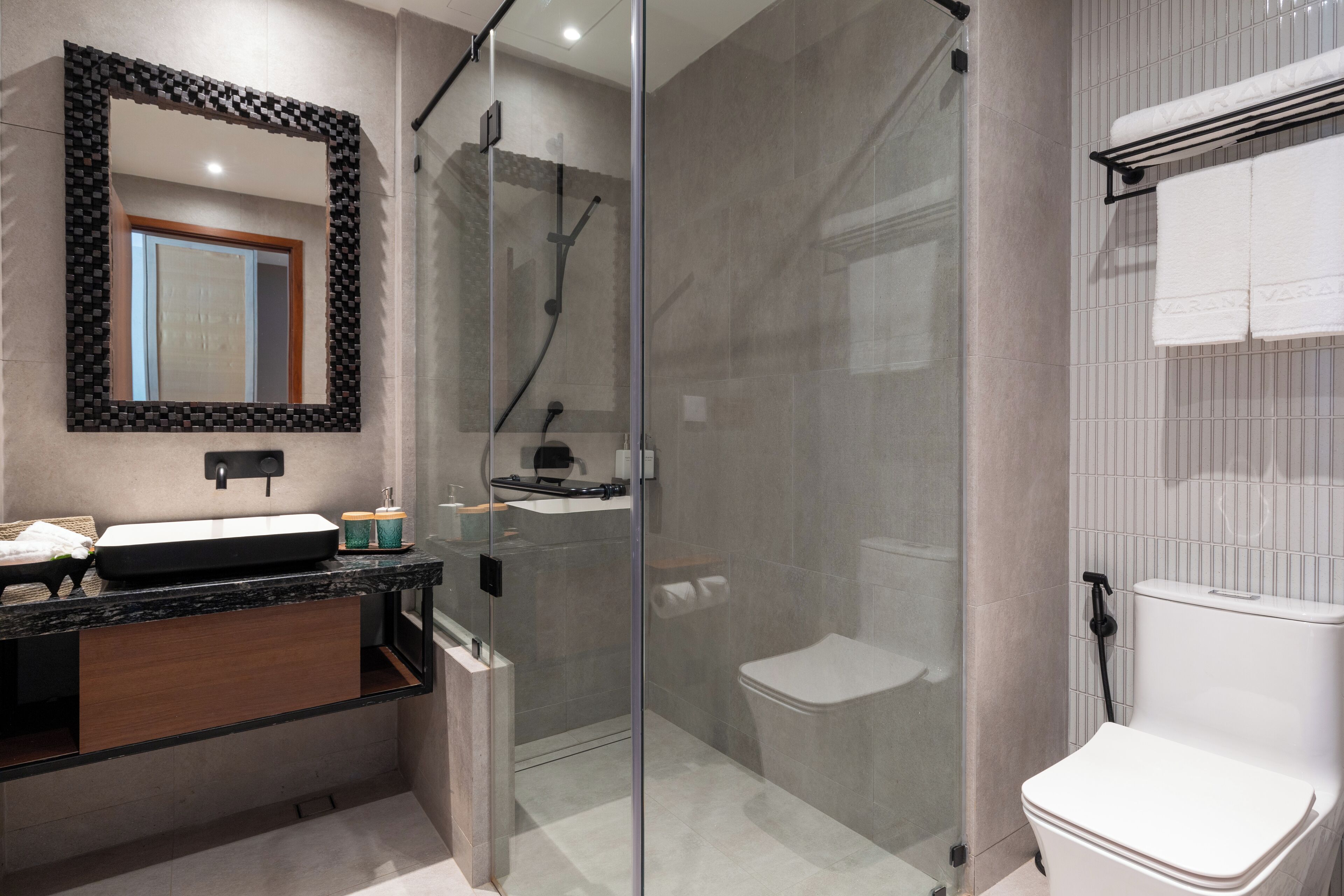Un baño moderno con ducha de vidrio, inodoro blanco y tocador con espejo y lavamanos.