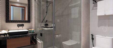 Un baño moderno con ducha de vidrio, inodoro blanco y tocador con espejo y lavamanos.