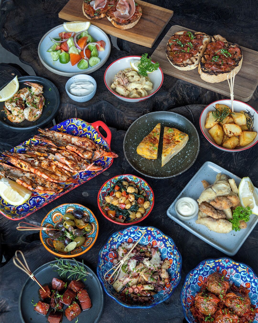 Un assortiment de plats comprenant des crevettes grillées, une salade et plusieurs plats différents.