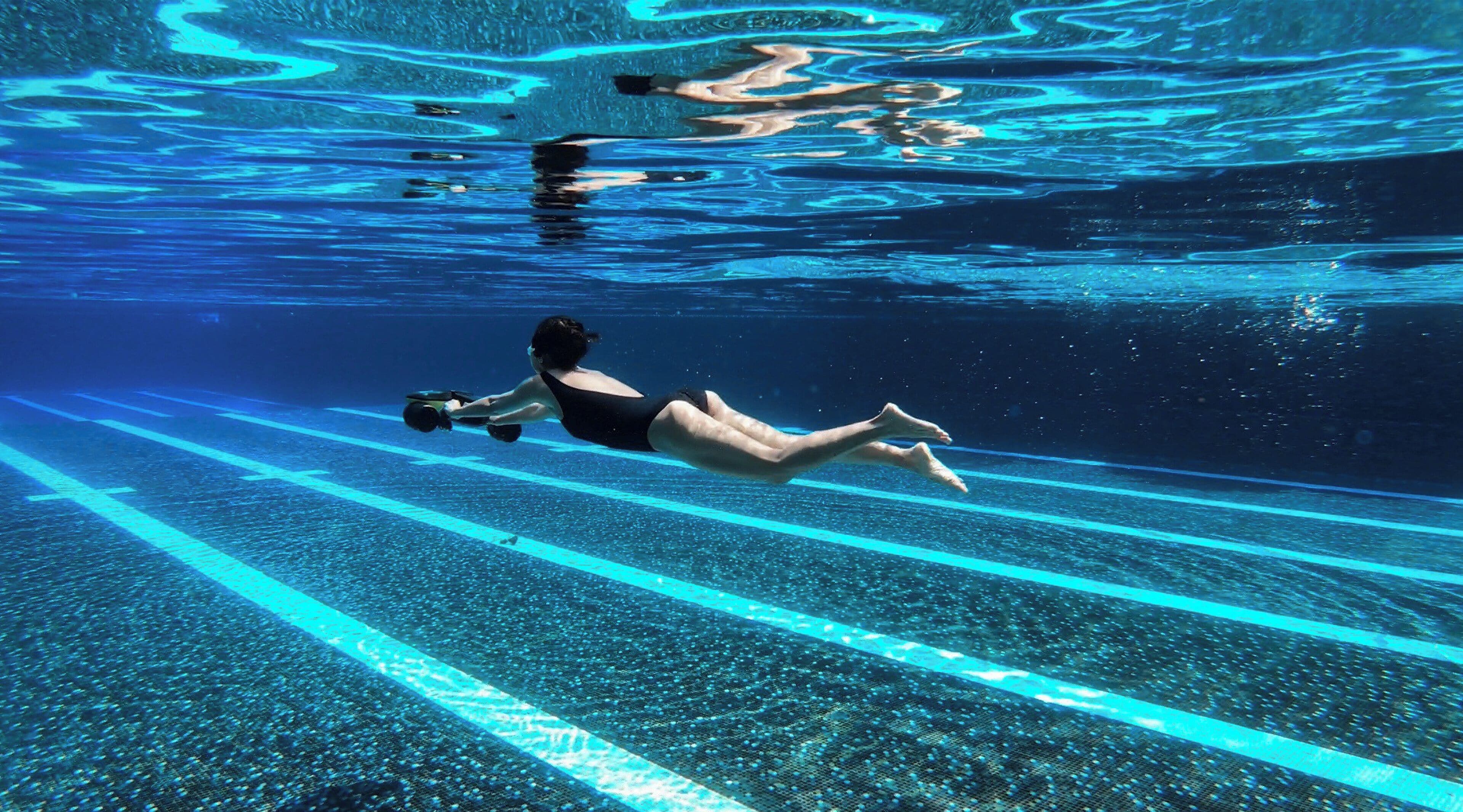A person swimming in a pool with lane markings.
