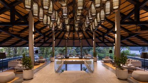 A spacious indoor area with a central glass table surrounded by seating, large columns, and hanging light fixtures. - Varana Hotel Krabi (Krabi)