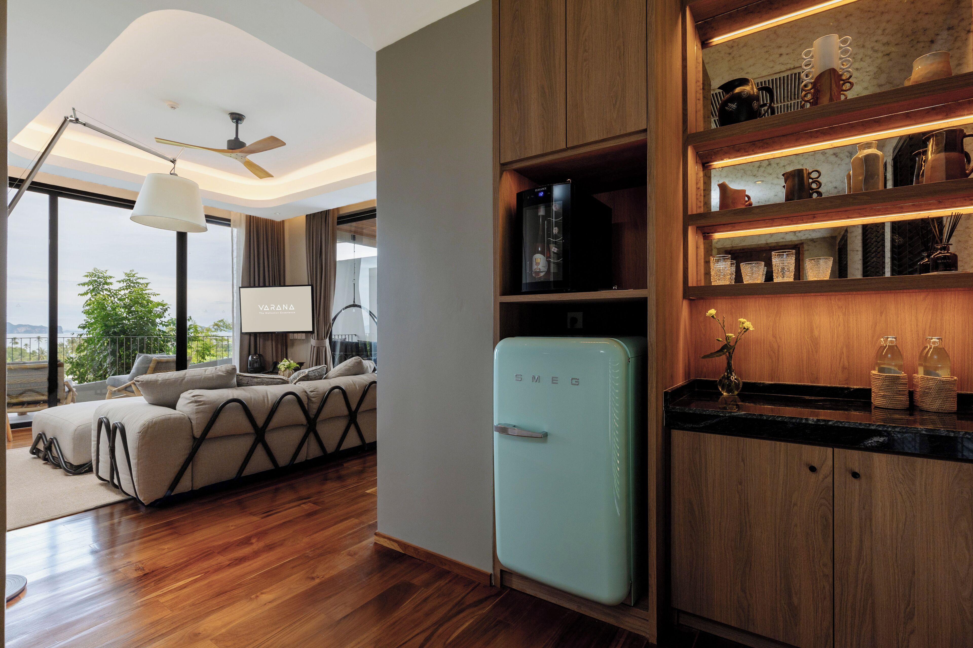 A modern kitchen with a vintage-style refrigerator, wooden cabinets, and a dining area with a sofa and table.