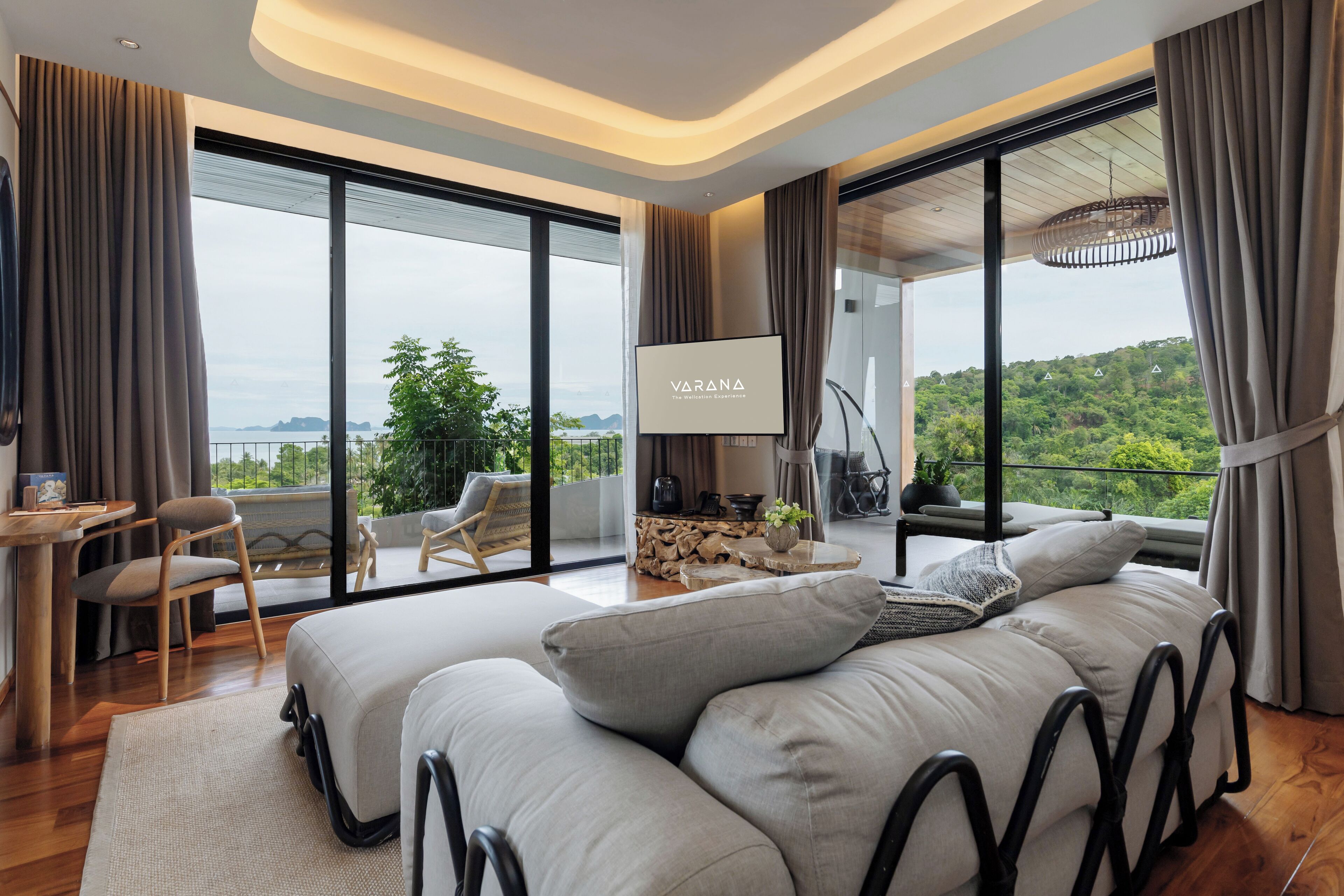 A modern bedroom with a large bed, a desk, and a view of the outdoors.