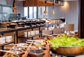 Een buffetopstelling met diverse food stations, waaronder een saladebar, kommen en borden.