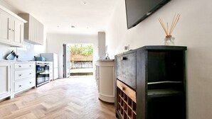 A modern kitchen with white cabinetry, a built-in oven, and a large black cabinet. - Moorland House by Switchback Stays (Cardiff)