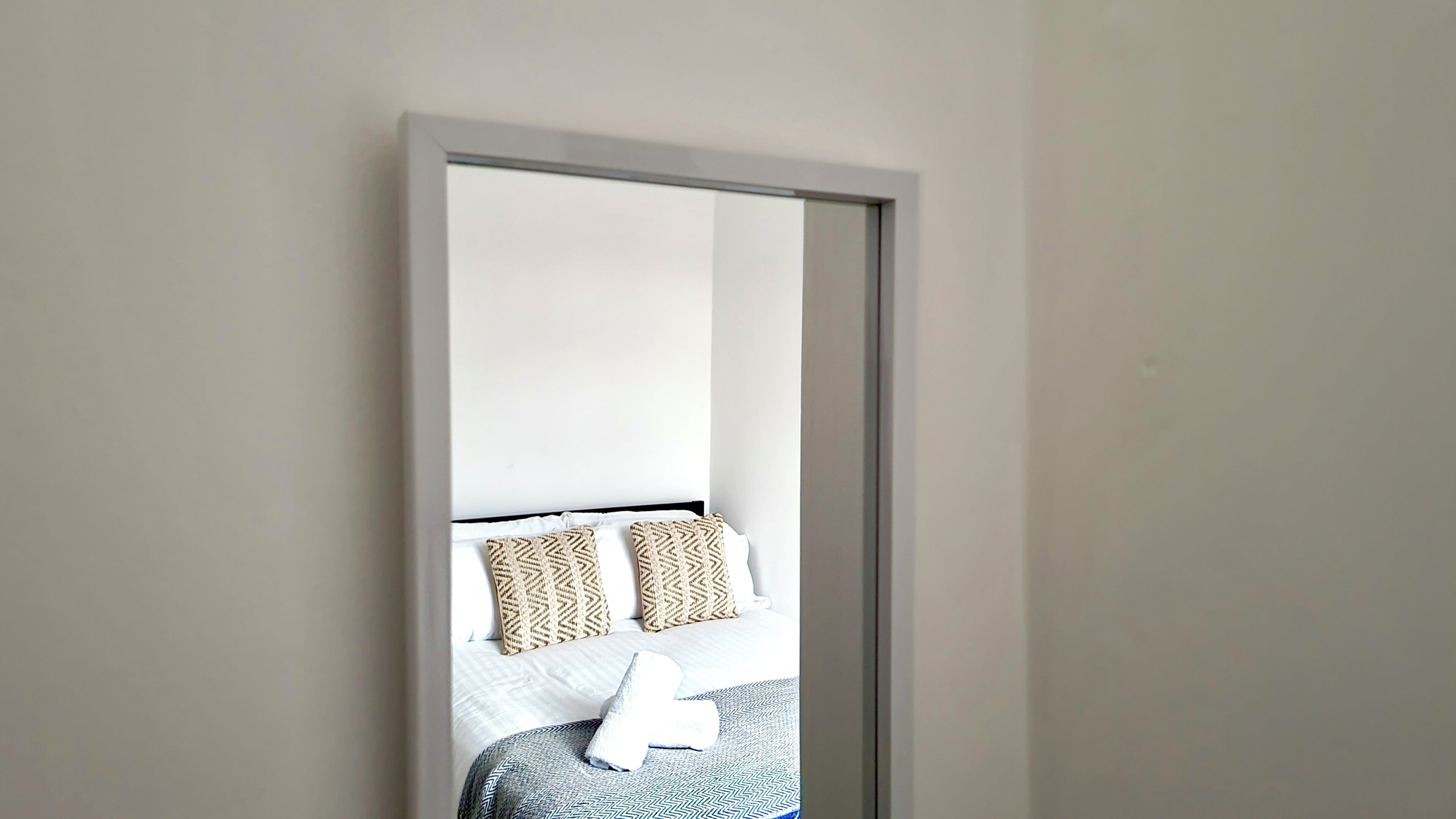 A room with a bed, pillows, and a white wall.