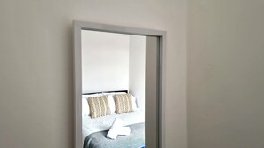 A room with a bed, pillows, and a white wall. - Thompson Apartments No.3 by Switchback Stays (Cardiff)