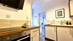 Una cocina moderna con televisor de pantalla plana, cafetera y lavamanos con grifo.