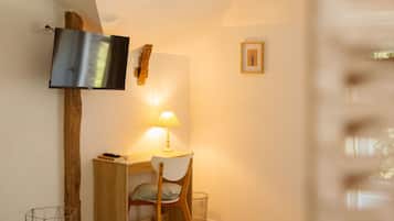 Un dormitorio con una cama, un escritorio, una silla, un televisor montado en la pared y una lámpara.