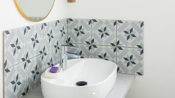 Un baño con lavamanos blanco, un espejo y baldosas con diseño geométrico.