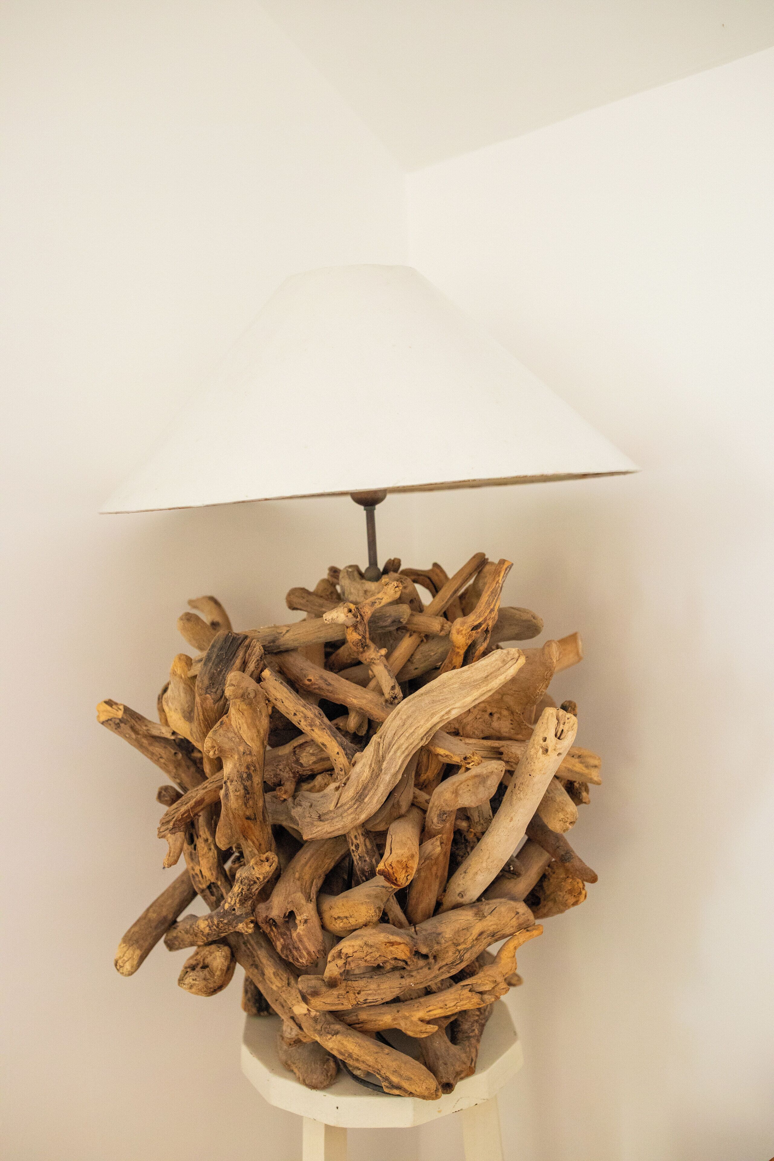 A lamp with a white shade and a base made of stacked logs.